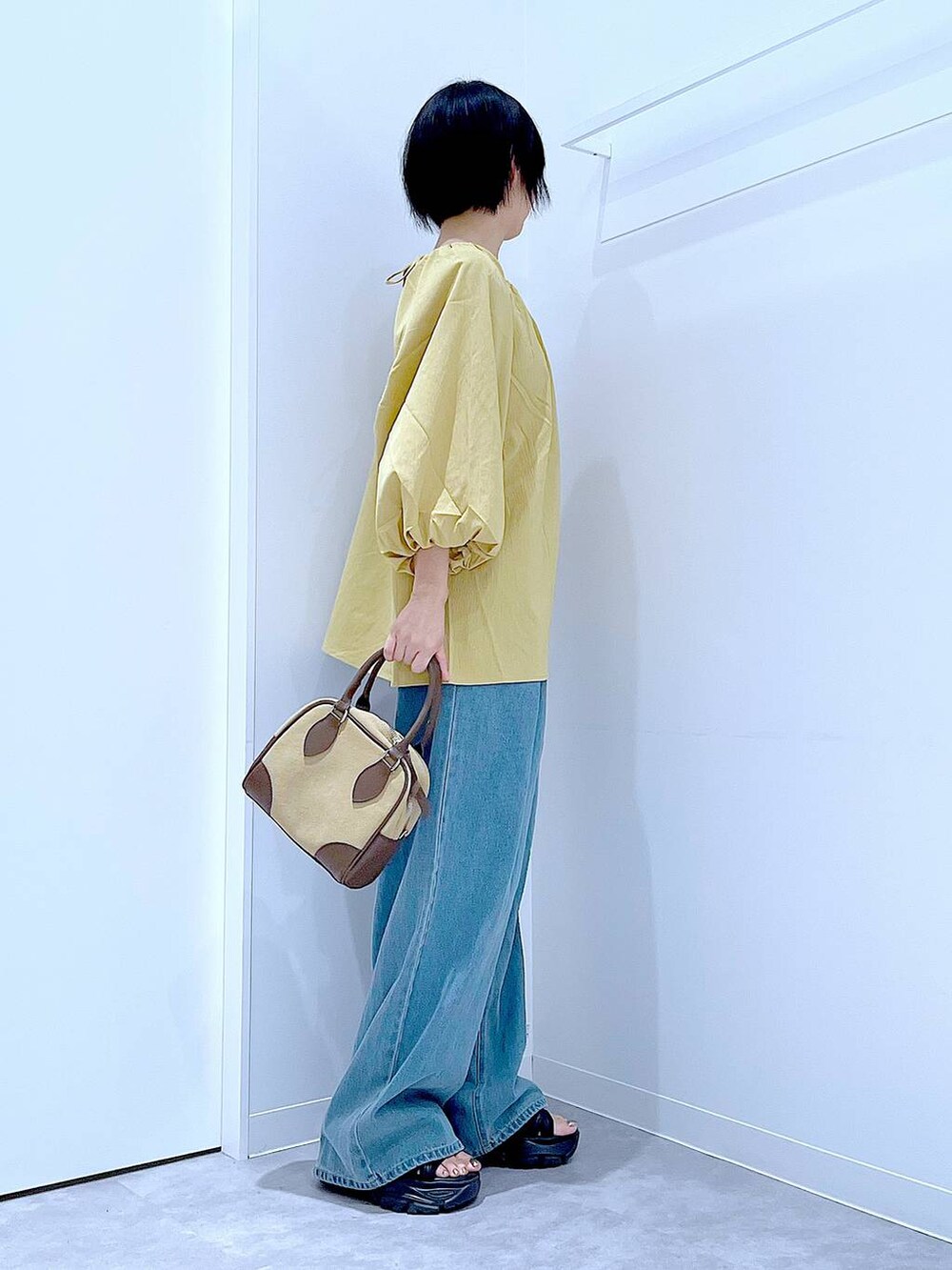 ブラック系のスニーカー、ブルー系のデニムパンツ、イエロー系のシャツ/ブラウスを着用したレディースの秋コーディネートの4枚目の写真