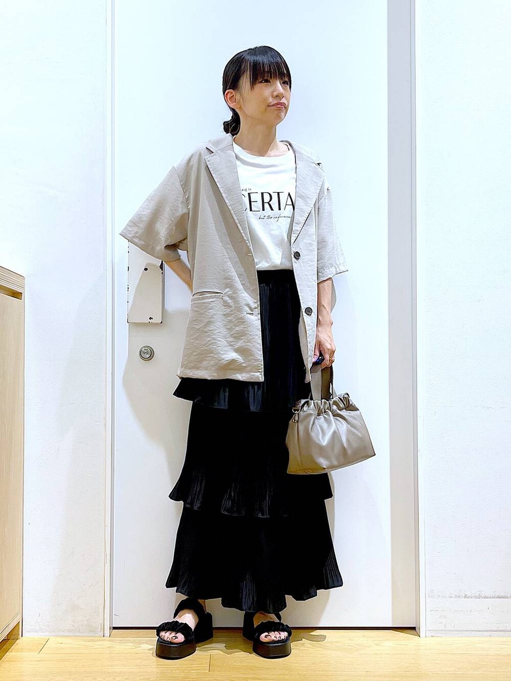 ブラック系のスカート、ブラック系のサンダル、ブラウン系のショルダーバッグを着用したレディースの夏コーディネートの2枚目の写真