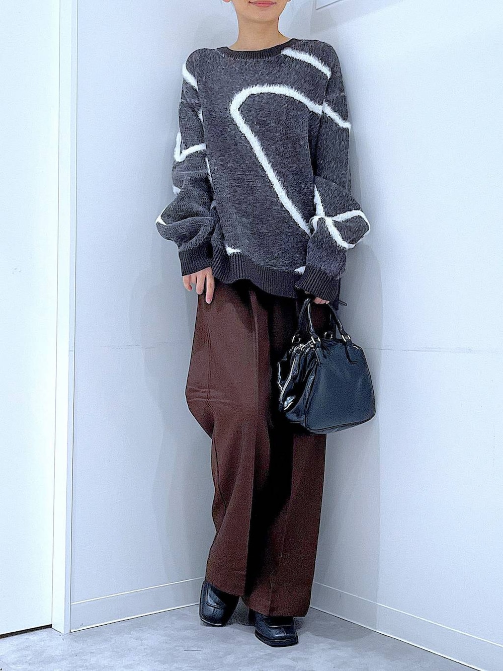 ブラック系のブーツ、ブラウン系のスラックス、ブラック系のショルダーバッグを着用したレディースの冬コーディネートの6枚目の写真