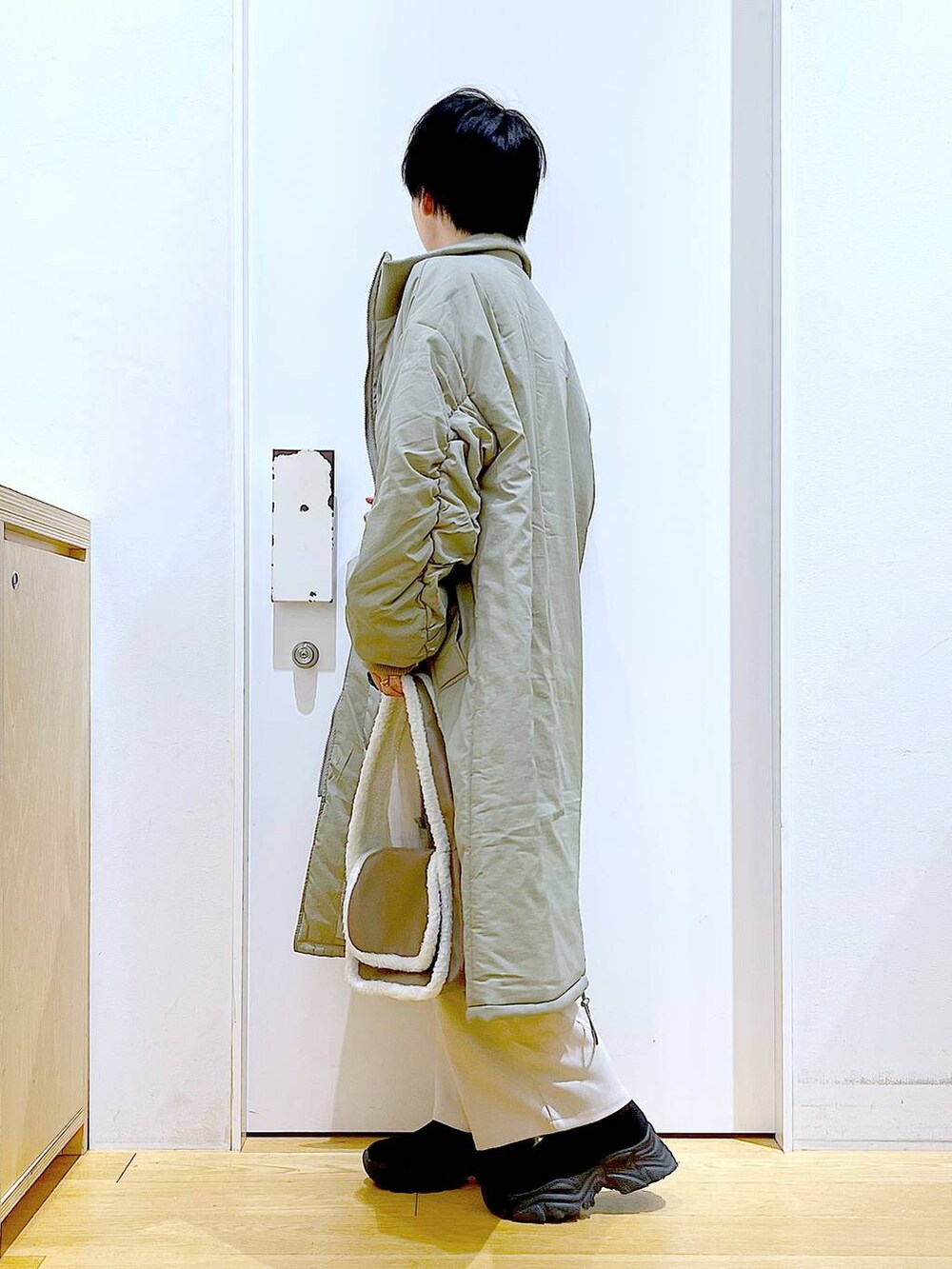 ブラック系のニット/セーター、ベージュ系のショルダーバッグ、ブラック系のブーツを着用したレディースの冬コーディネートの3枚目の写真