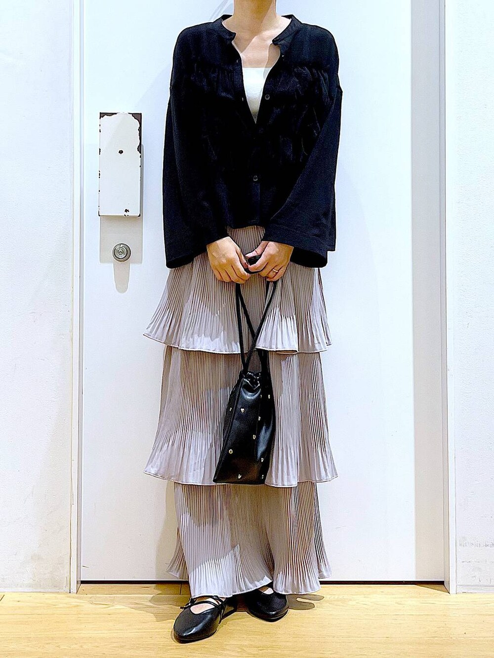 グレー系のスカート、ブラック系のショルダーバッグ、ブラック系のパンプスを着用したレディースの秋コーディネートの6枚目の写真