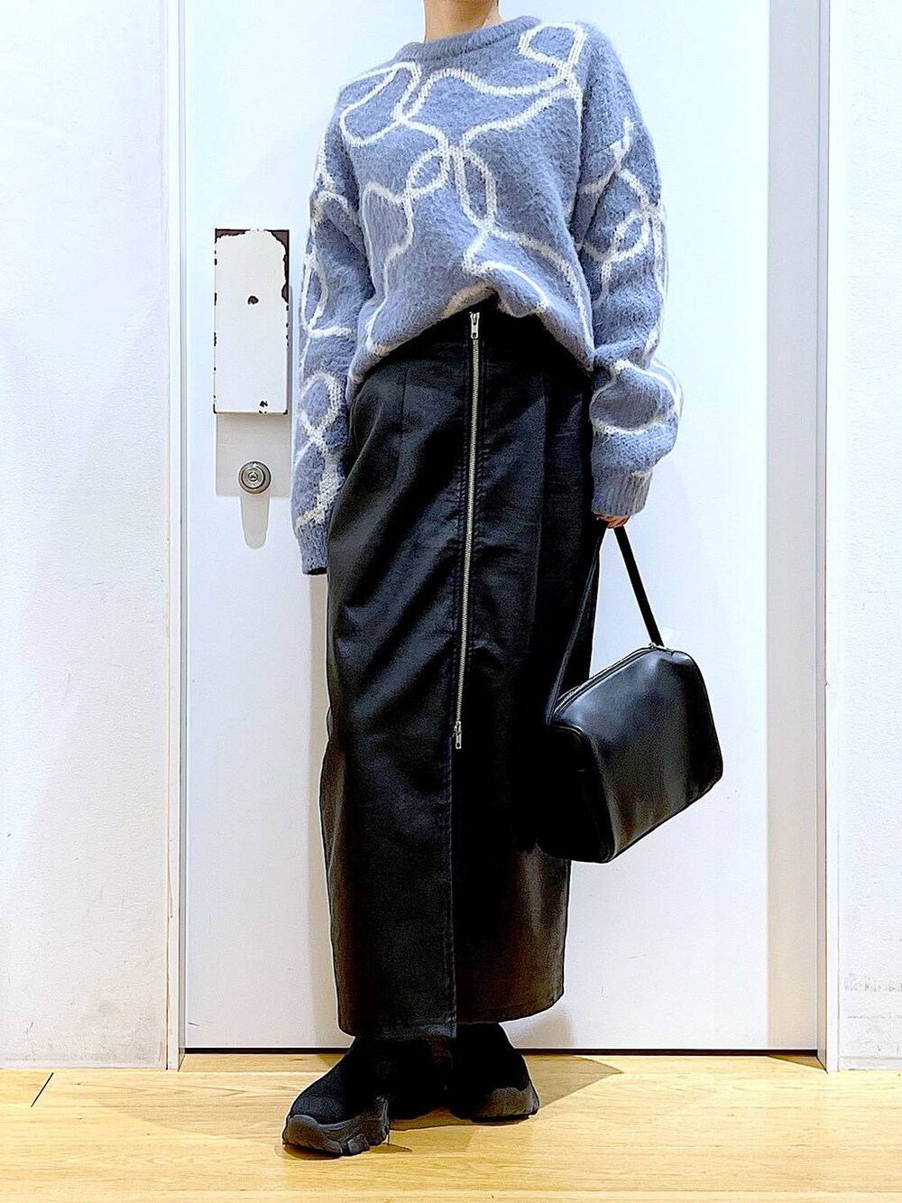 ブラック系のスカート、ブラック系のショルダーバッグ、ブラック系のブーツを着用したレディースの冬コーディネートの6枚目の写真