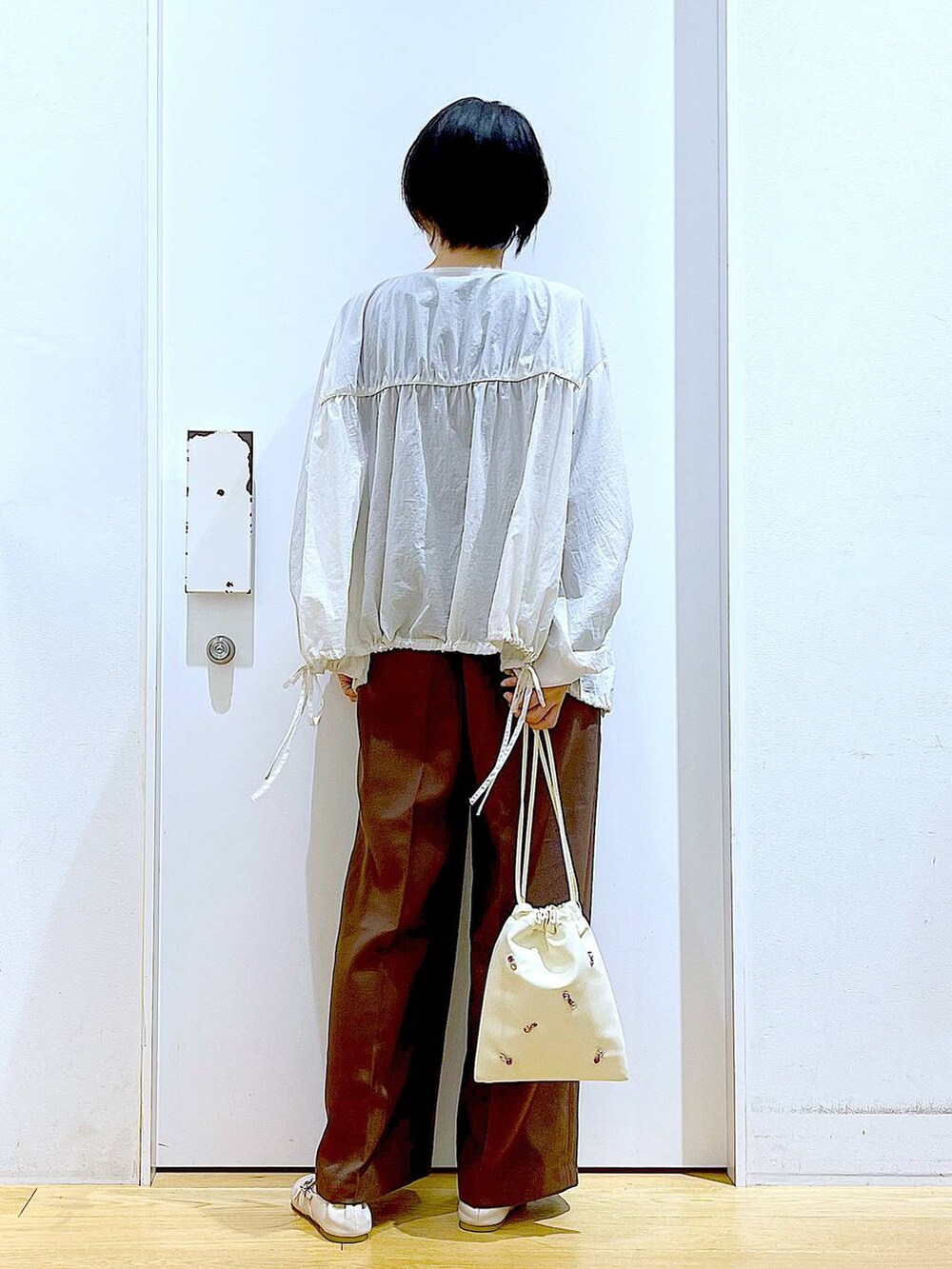 ホワイト系のショルダーバッグ、ホワイト系のパンプス、ブラック系のTシャツ/カットソーを着用したレディースの秋コーディネートの5枚目の写真