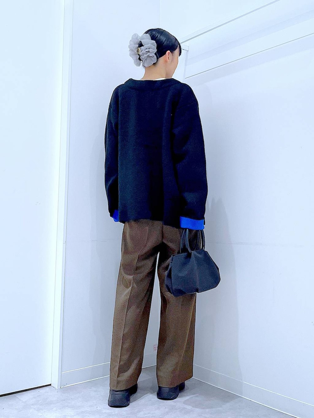 ブラック系のハンドバッグ、ブラウン系のスラックス、ホワイト系のTシャツ/カットソーを着用したレディースの秋コーディネートの5枚目の写真