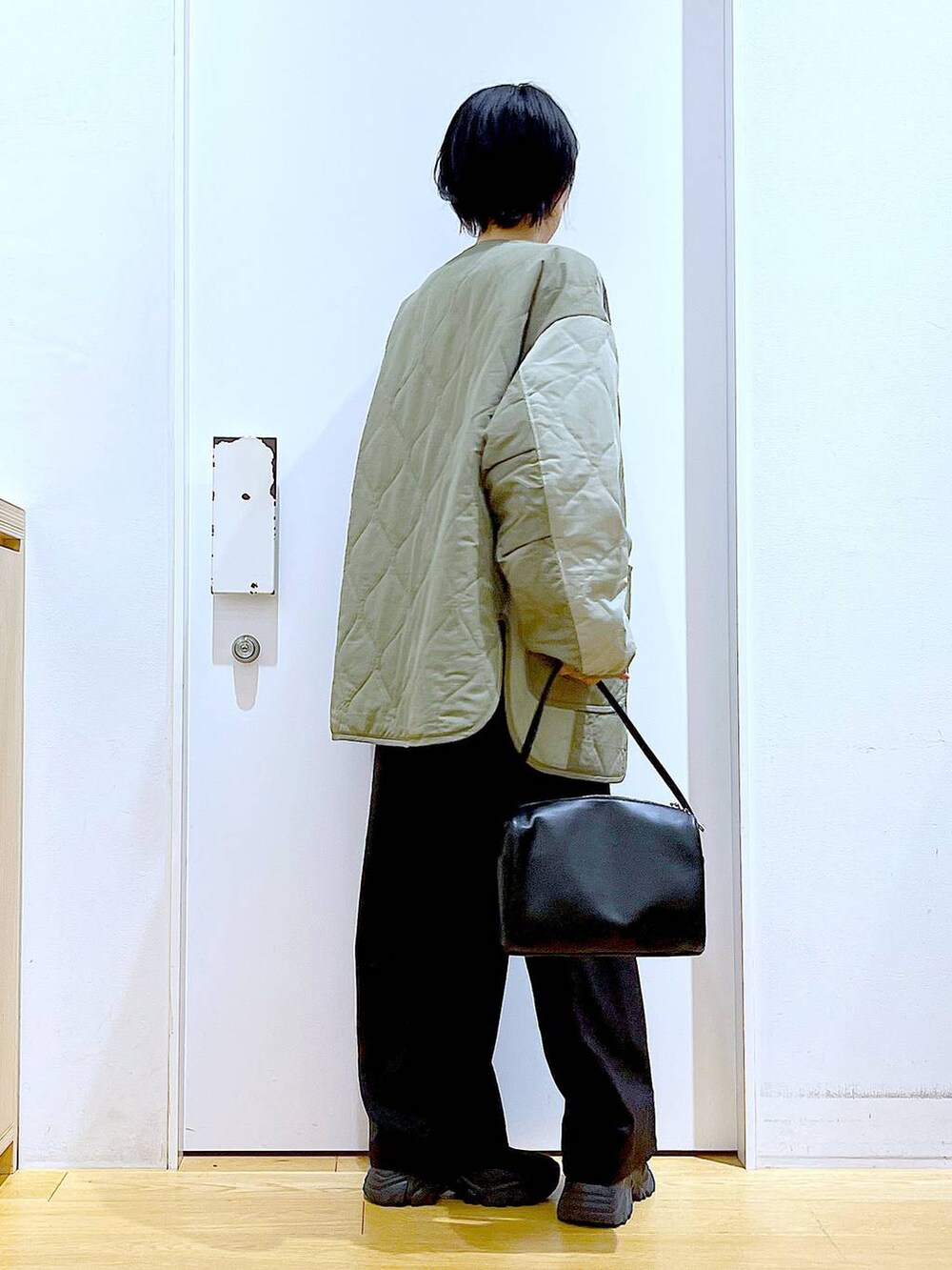 ブラック系のショルダーバッグ、ホワイト系のスウェット、ブラック系のブーツを着用したレディースの秋コーディネートの4枚目の写真