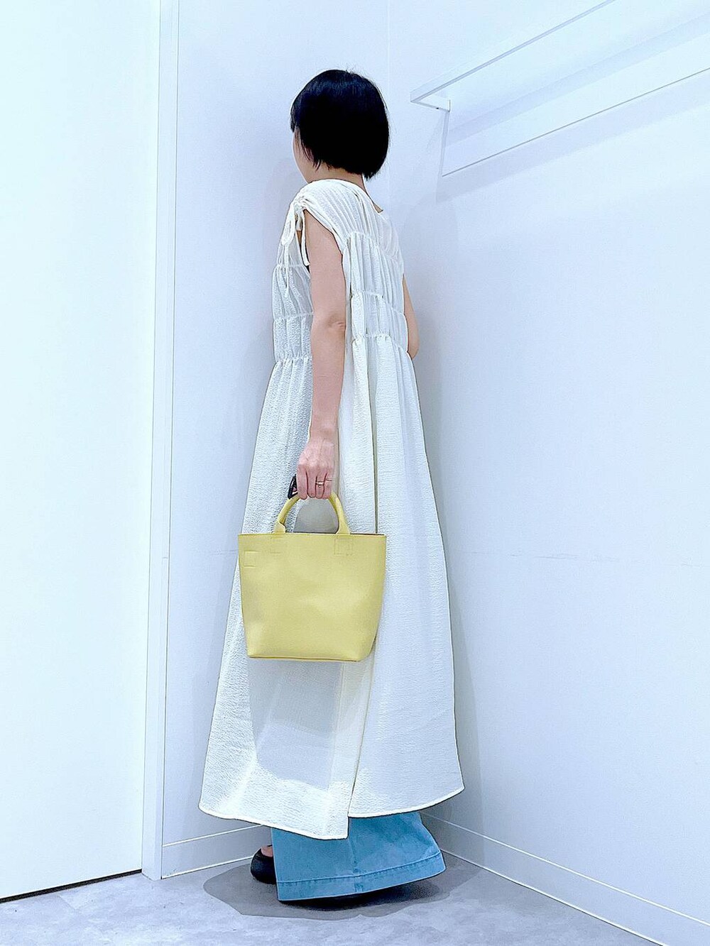 ブラック系のサンダル、ブルー系のデニムパンツ、ベージュ系のワンピースを着用したレディースの夏コーディネートの3枚目の写真