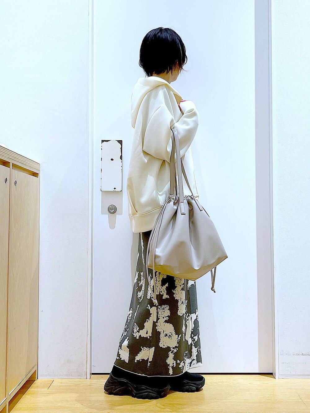 グレー系のスカート、ベージュ系のトートバッグ、ブラック系のブーツを着用したレディースの秋コーディネートの4枚目の写真