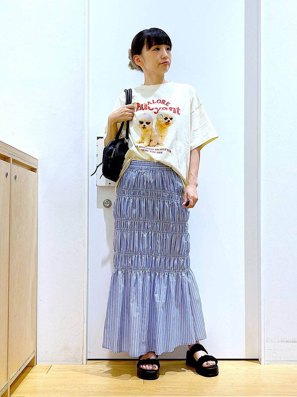 ブラック系のサンダル、その他のスカート、ブラック系のハンドバッグを着用したレディースの夏コーディネートの2枚目の写真