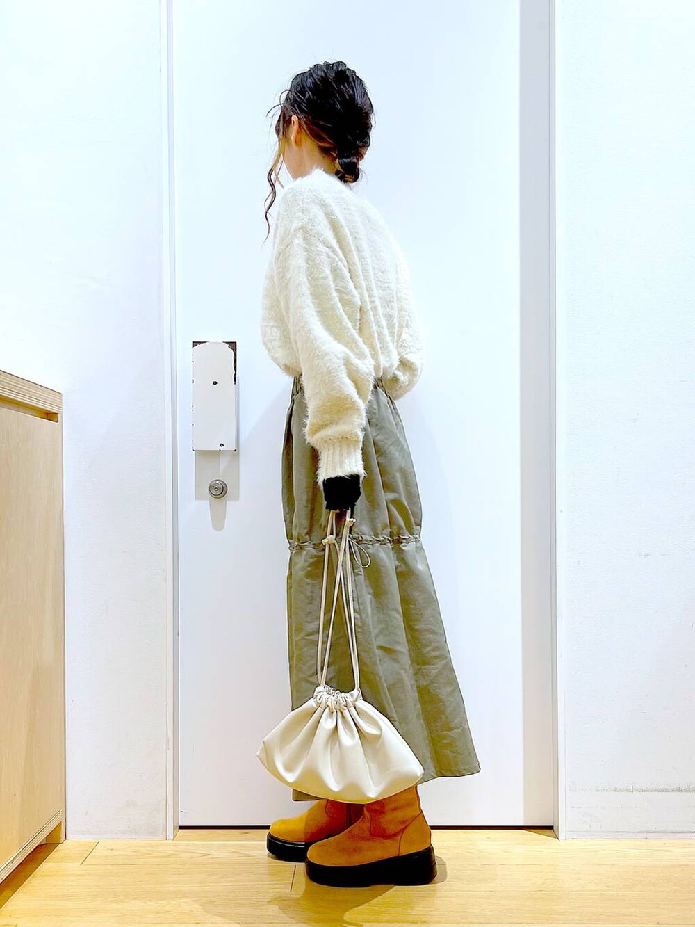 ベージュ系のショルダーバッグ、ベージュ系のブーツ、ベージュ系のニット/セーターを着用したレディースの冬コーディネートの3枚目の写真