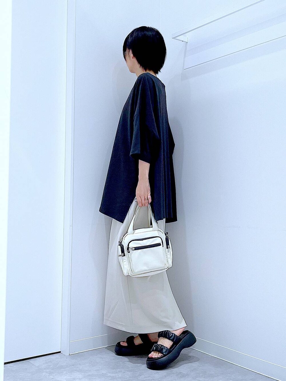 ブラック系のサンダル、ベージュ系のスカート、ホワイト系のショルダーバッグを着用したレディースの夏コーディネートの3枚目の写真