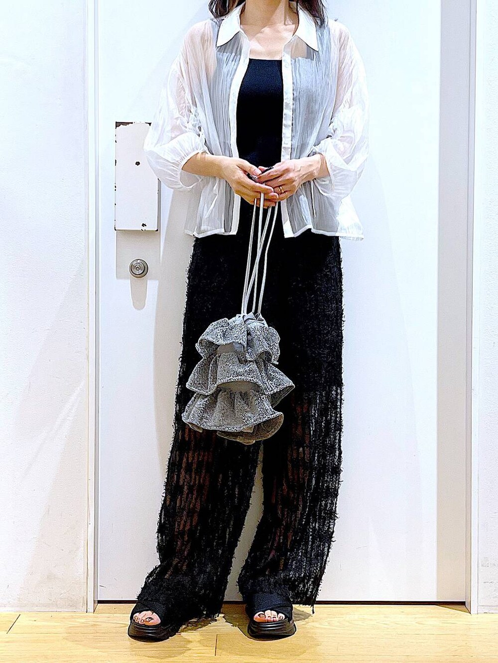 シルバー系のショルダーバッグ、ブラック系のニット/セーター、ブラック系のサンダルを着用したレディースの夏コーディネートの6枚目の写真