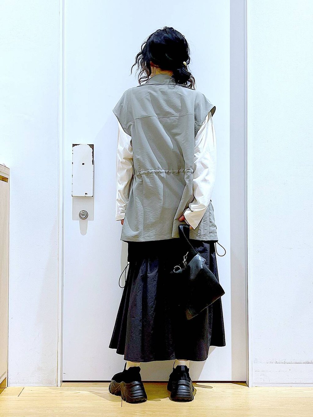 ブラック系のショルダーバッグ、ブラック系のスニーカー、ブラック系のスカートを着用したレディースの春コーディネートの5枚目の写真