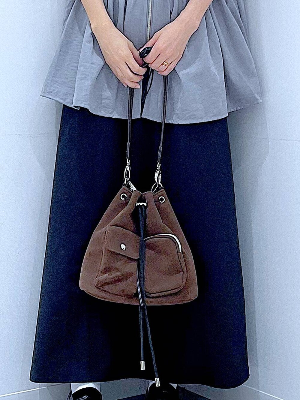 ブラック系のスカート、ブラック系のローファー、ブラウン系のショルダーバッグを着用したレディースの秋コーディネートの9枚目の写真