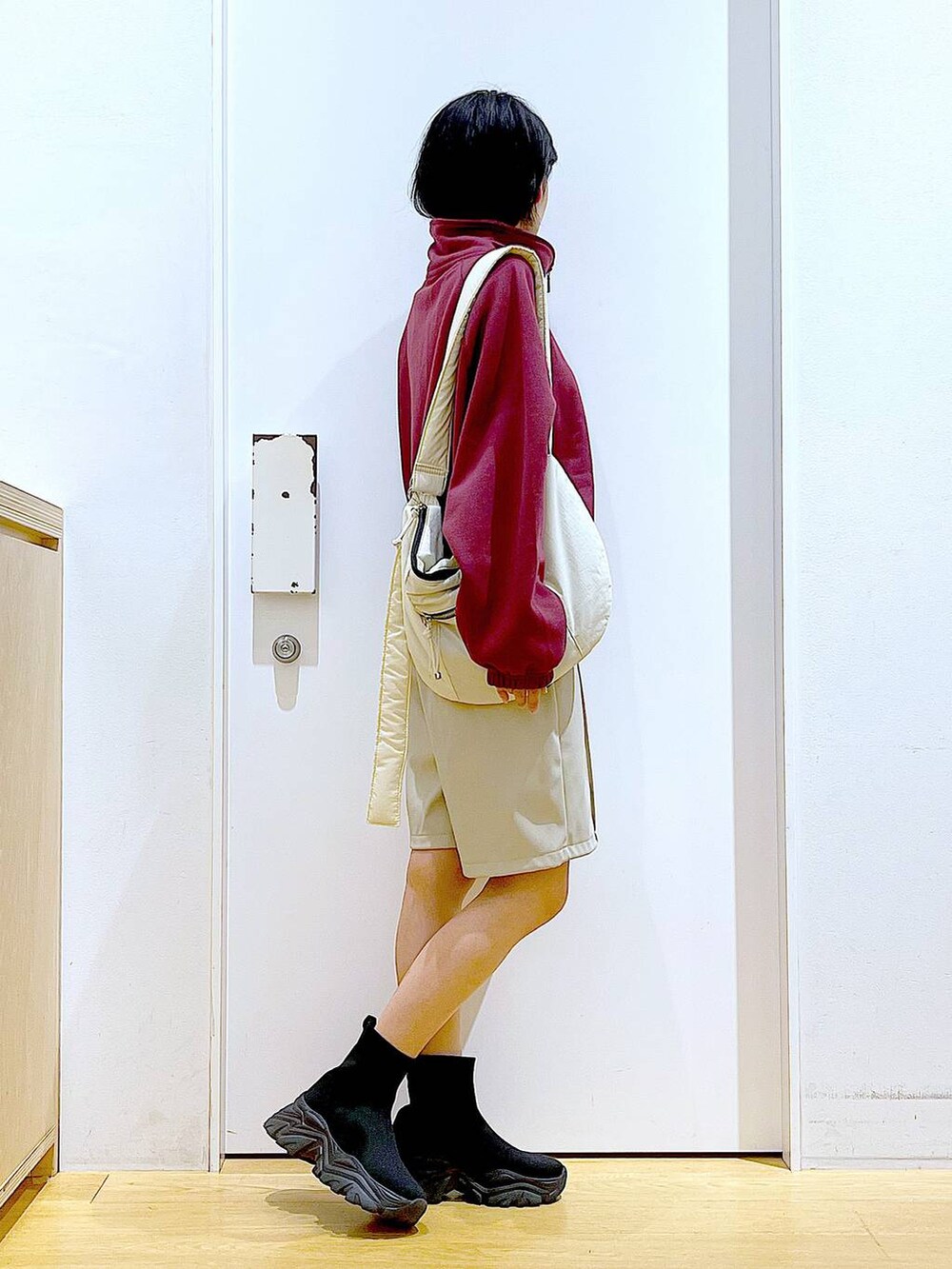 ホワイト系のショルダーバッグ、ブラック系のブーツ、レッド系のスウェットを着用したレディースの冬コーディネートの4枚目の写真