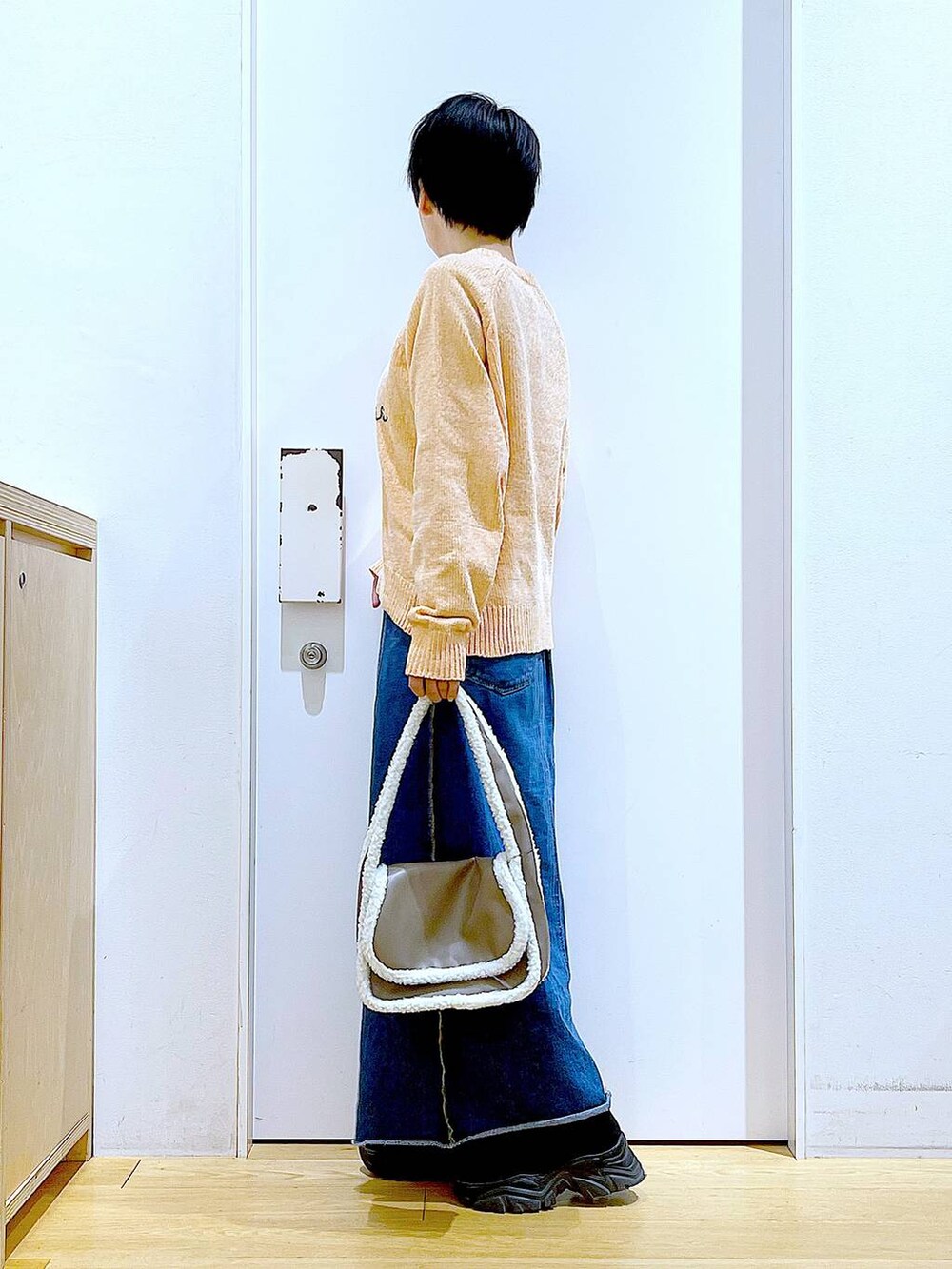 ブルー系のデニムスカート、ベージュ系のショルダーバッグ、ブラック系のブーツを着用したレディースの冬コーディネートの3枚目の写真