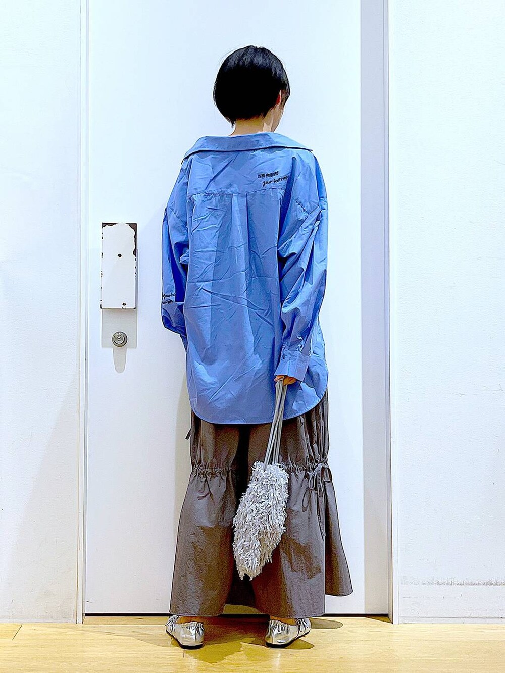 グレー系のショルダーバッグ、シルバー系のパンプス、グレー系のスカートを着用したレディースの秋コーディネートの5枚目の写真