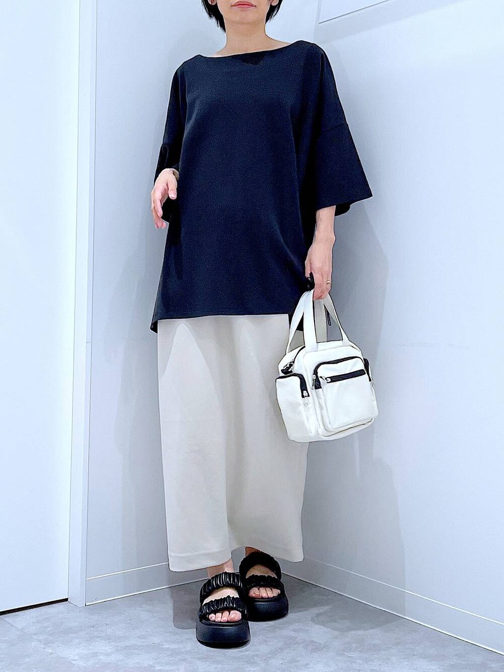 ブラック系のサンダル、ベージュ系のスカート、ホワイト系のショルダーバッグを着用したレディースの夏コーディネートの6枚目の写真