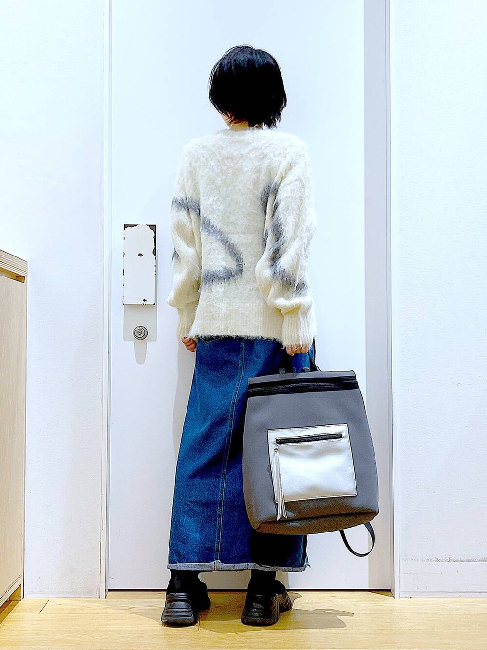ホワイト系のニット/セーター、グレー系のバックパック/リュック、ブルー系のデニムスカートを着用したレディースの冬コーディネートの5枚目の写真