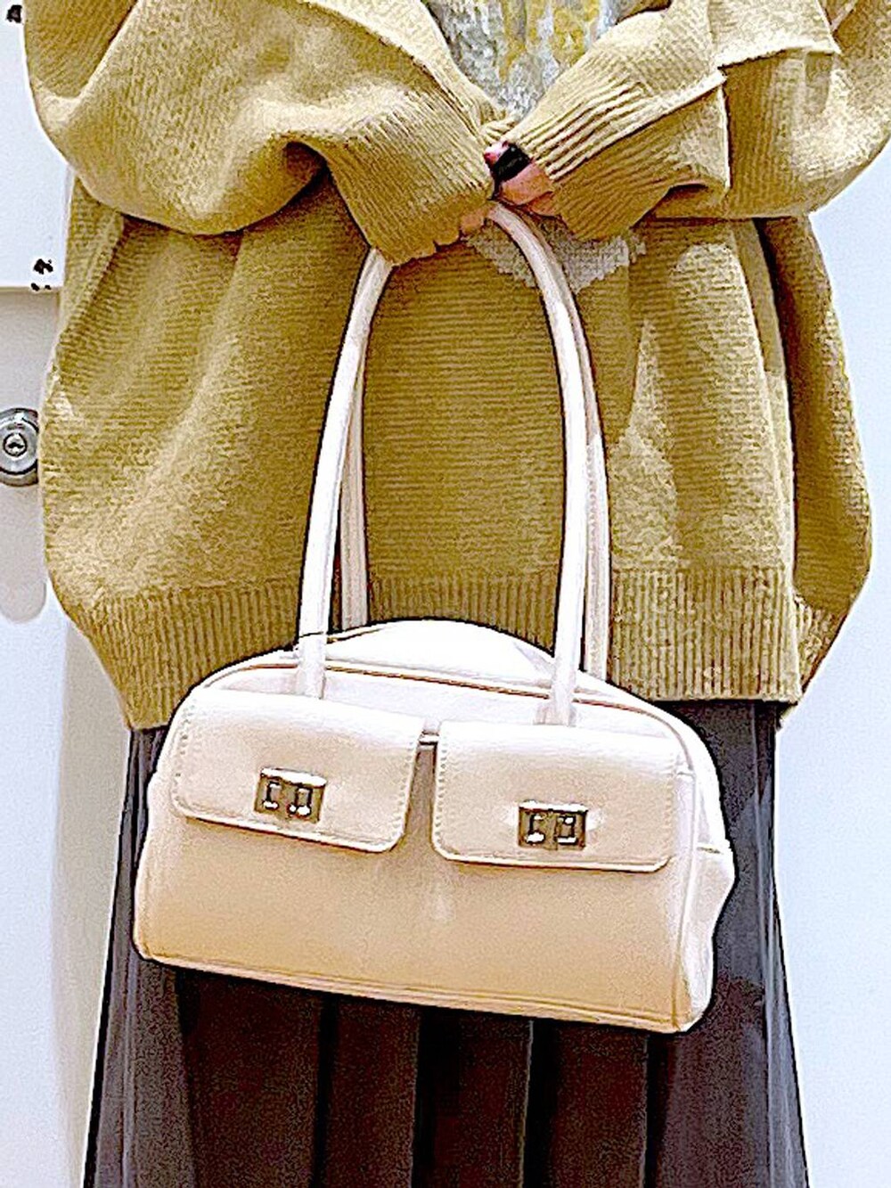 ホワイト系のハンドバッグ、ブラック系のブーツ、グレー系のスカートを着用したレディースの冬コーディネートの9枚目の写真