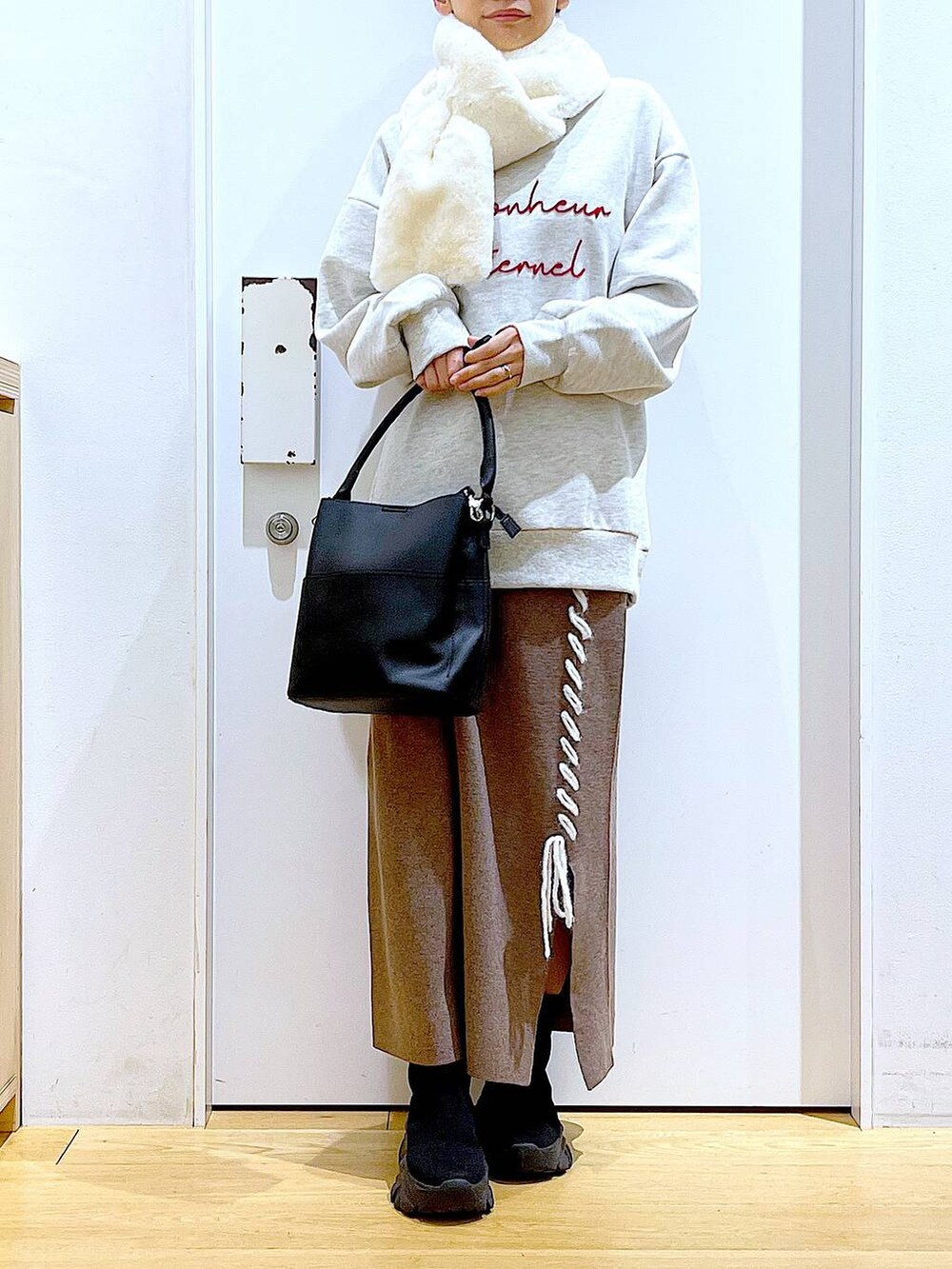 ブラック系のショルダーバッグ、ブラック系のブーツ、ブラウン系のスカートを着用したレディースの冬コーディネートの6枚目の写真