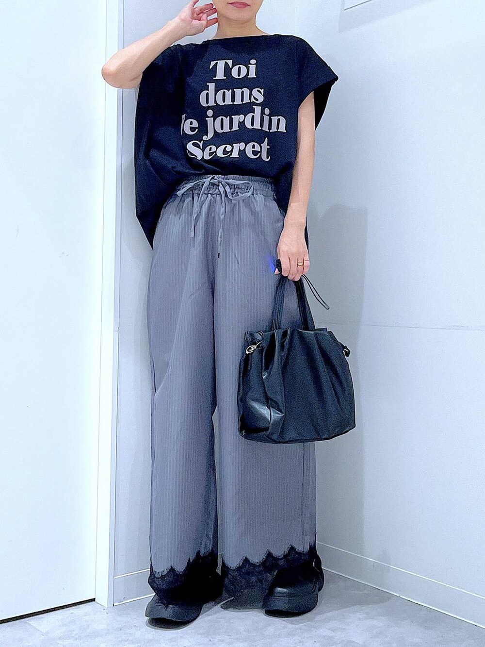 ブラック系のTシャツ/カットソー、グレー系のスラックス、ブラック系のハンドバッグを着用したレディースの秋コーディネートの6枚目の写真