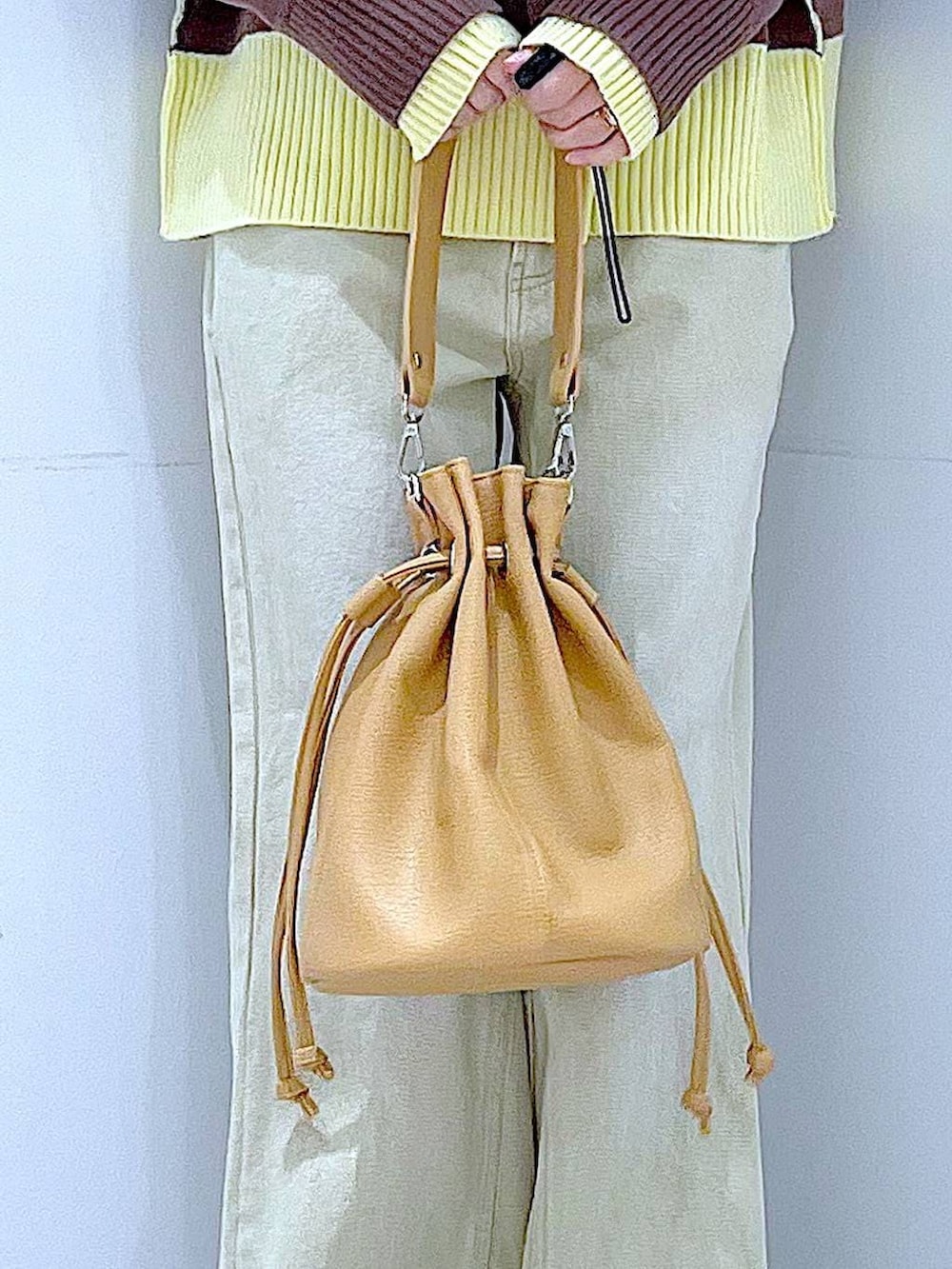 ブラウン系のニット/セーター、ベージュ系のデニムパンツ、ブラウン系のショルダーバッグを着用したレディースの冬コーディネートの9枚目の写真