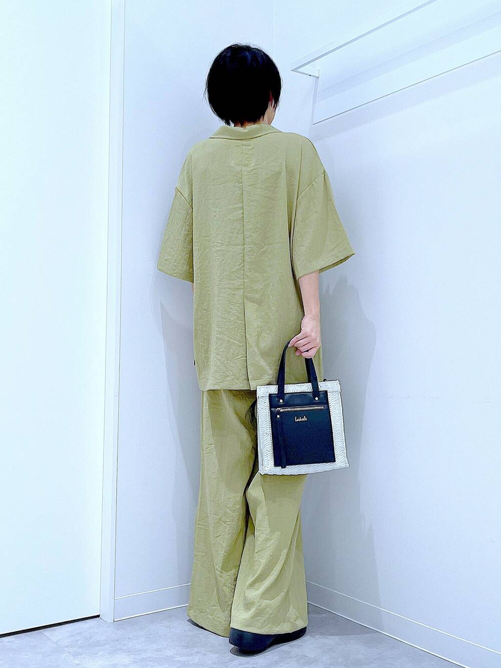 ホワイト系のショルダーバッグ、ブラック系のサンダル、グリーン系のテーラードジャケットを着用したレディースの夏コーディネートの5枚目の写真