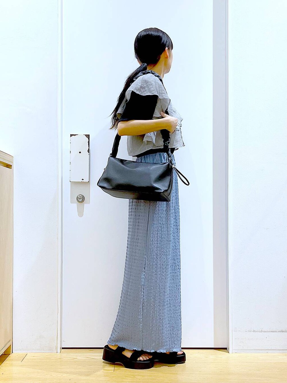 ブラック系のショルダーバッグ、ブルー系のスカート、ブラック系のTシャツ/カットソーを着用したレディースの夏コーディネートの4枚目の写真