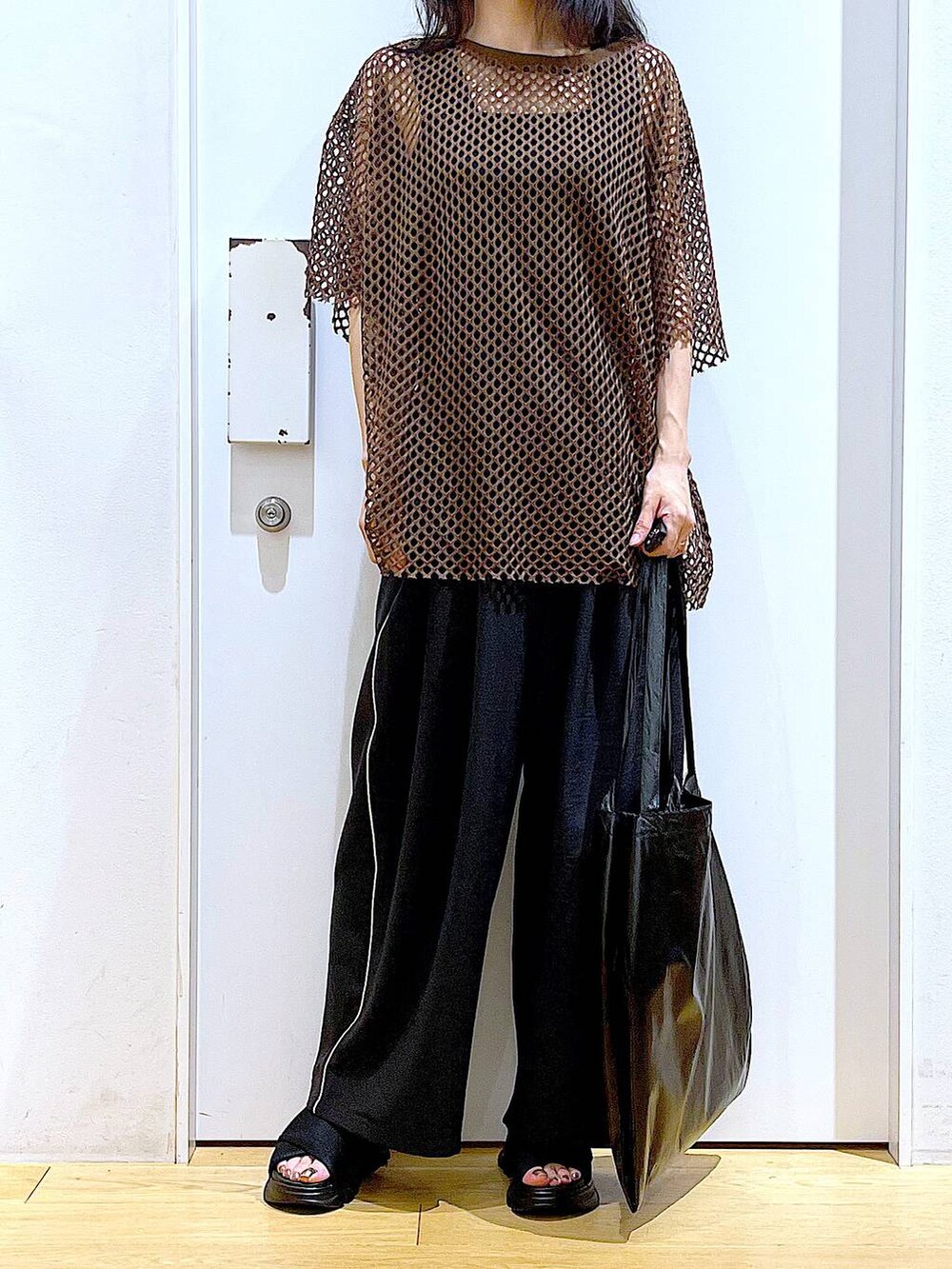 ブラック系のトートバッグ、ブラック系のニット/セーター、ブラック系のサンダルを着用したレディースの夏コーディネートの6枚目の写真