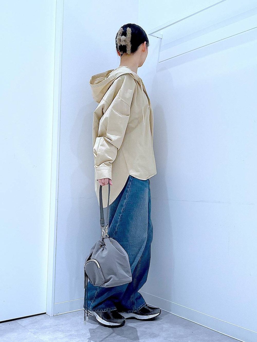 ブルー系のデニムパンツ、グレー系のショルダーバッグ、ベージュ系のその他トップスを着用したレディースの春コーディネートの4枚目の写真