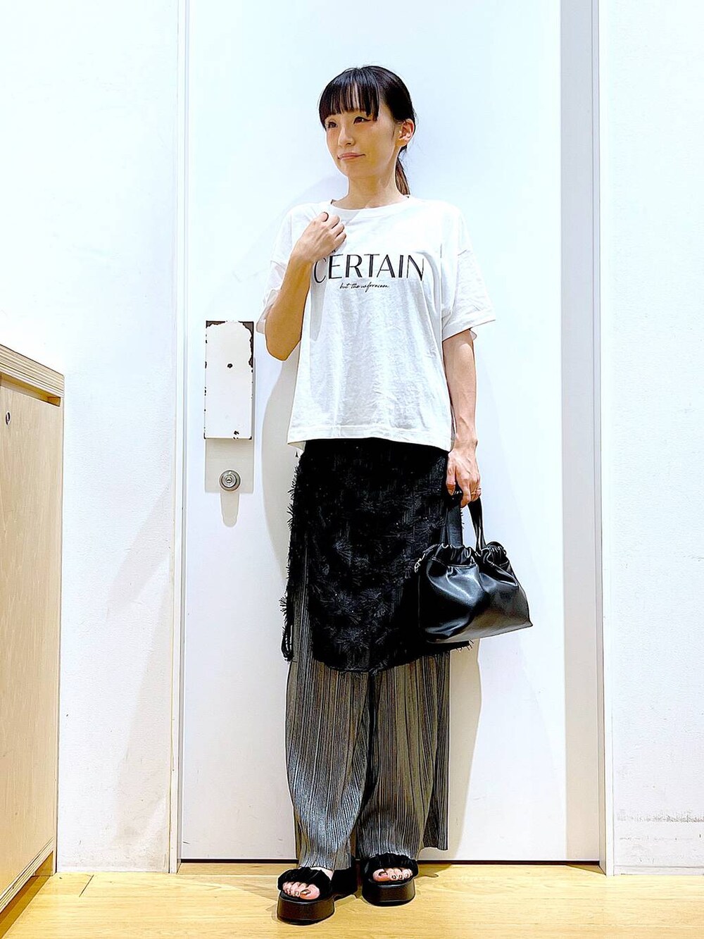 ブラック系のサンダル、ブラック系のショルダーバッグ、ブラック系のスカートを着用したレディースの秋コーディネートの2枚目の写真