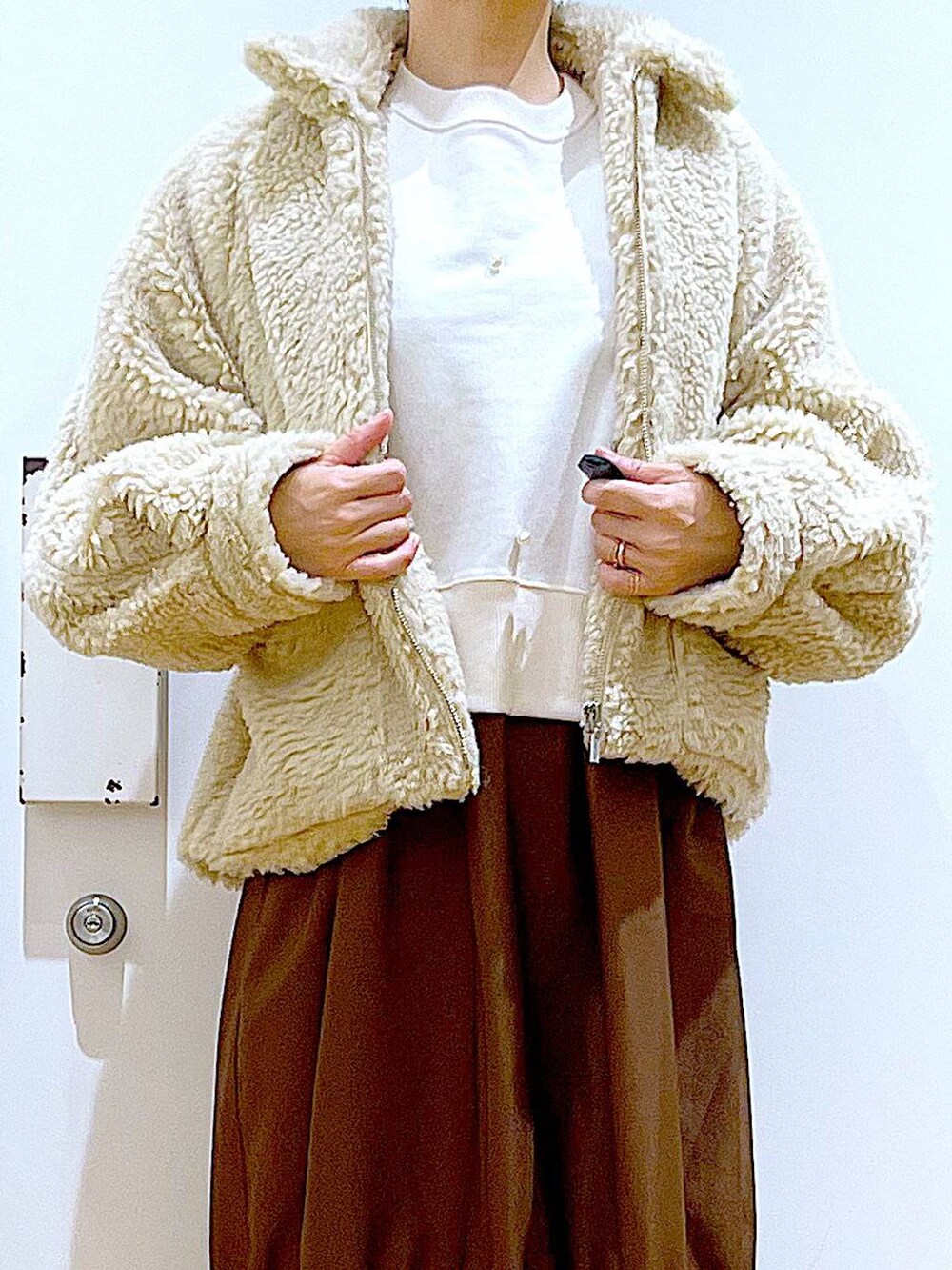 ホワイト系のブルゾン、ホワイト系のスウェット、ブラック系のブーツを着用したレディースの冬コーディネートの7枚目の写真