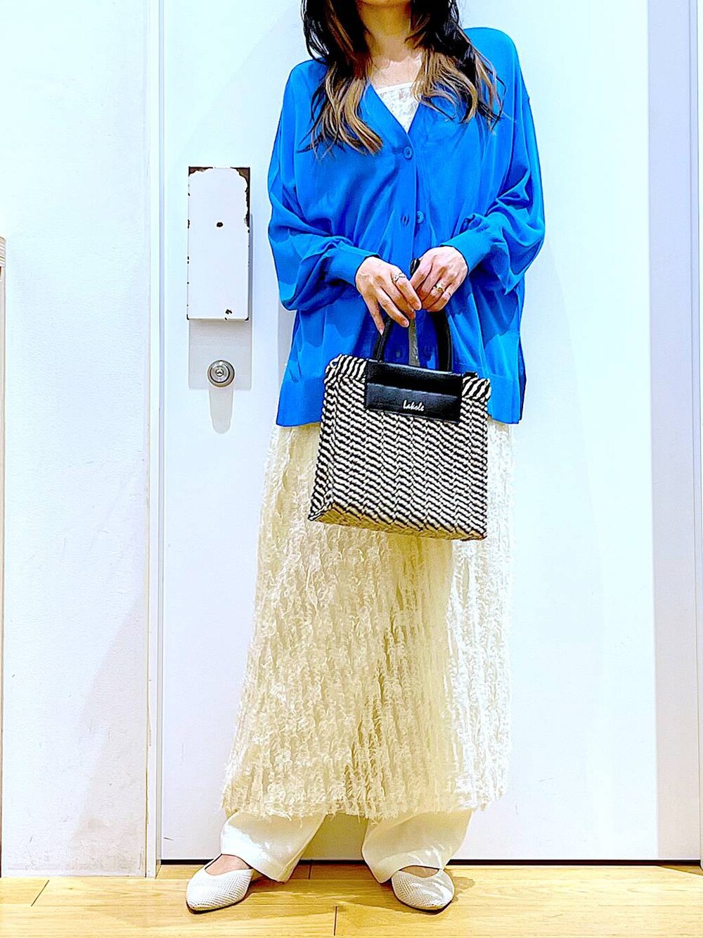 ホワイト系のその他パンツ、ブルー系のカーディガン/ボレロ、ホワイト系のパンプスを着用したレディースの春コーディネートの6枚目の写真