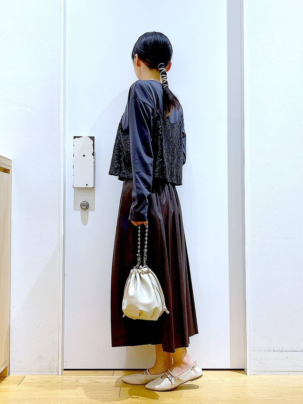 ベージュ系のショルダーバッグ、ホワイト系のパンプス、ブラック系のベストを着用したレディースの秋コーディネートの3枚目の写真