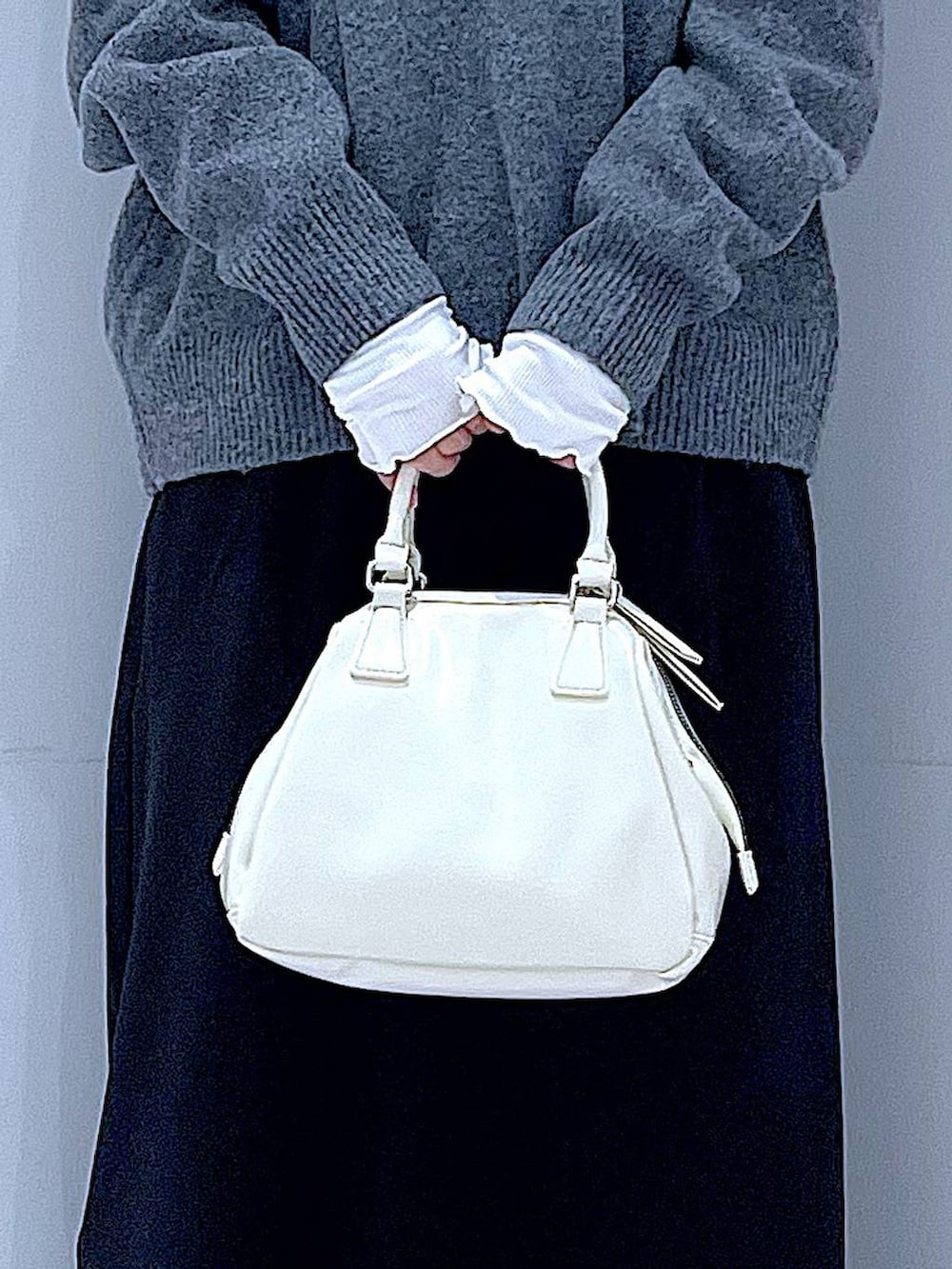 ブラック系のスカート、ブラック系のブーツ、ホワイト系のショルダーバッグを着用したレディースの冬コーディネートの9枚目の写真