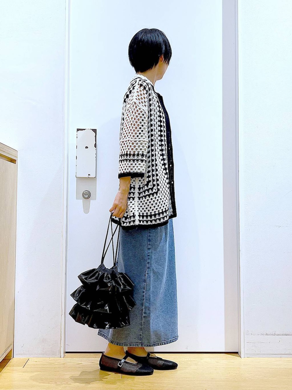ブラック系のショルダーバッグ、ブラック系のパンプス、ブルー系のジャンパースカートを着用したレディースの春コーディネートの4枚目の写真