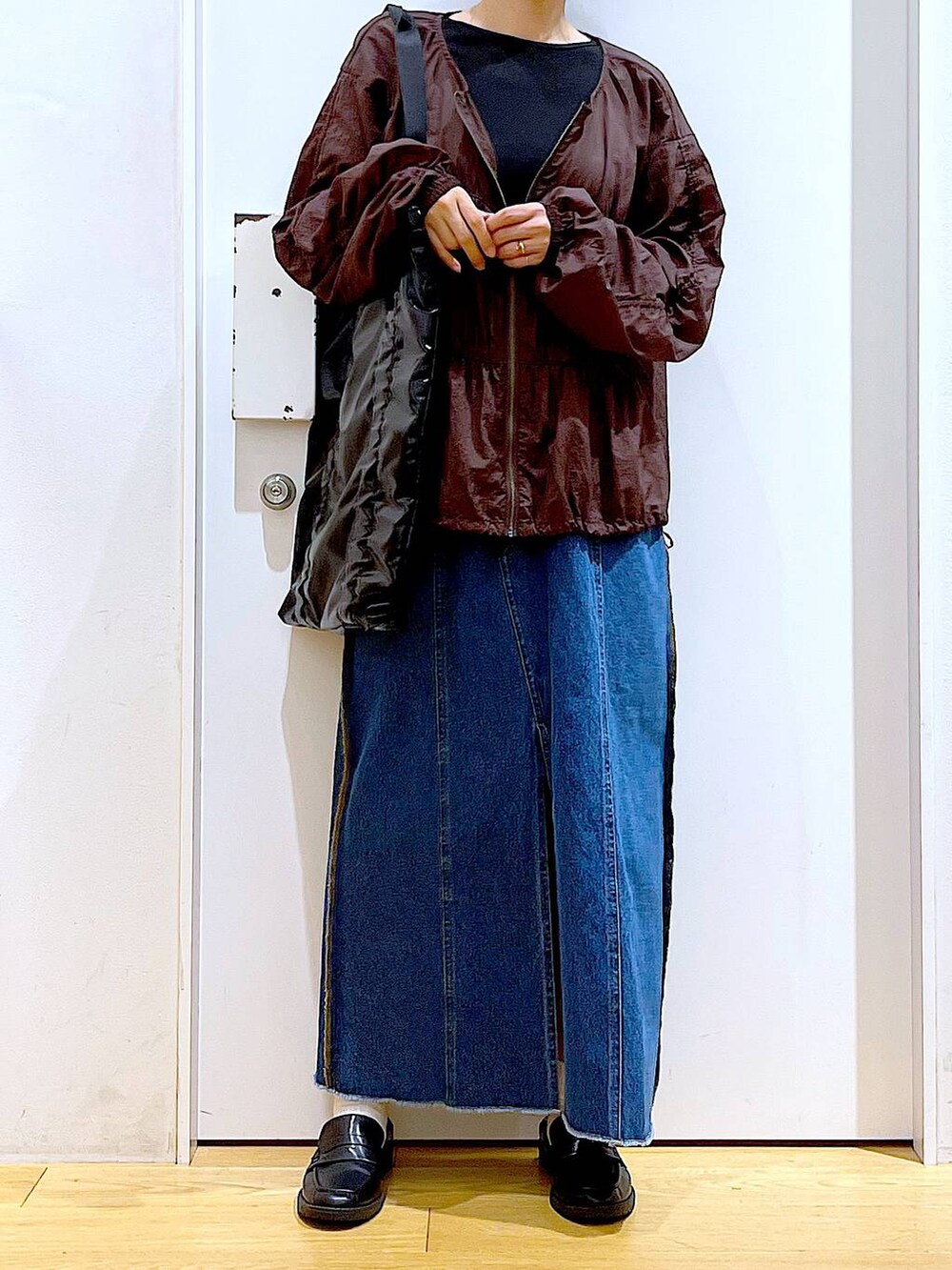 ブラック系のローファー、ブルー系のデニムスカート、ブラック系のTシャツ/カットソーを着用したレディースの秋コーディネートの6枚目の写真