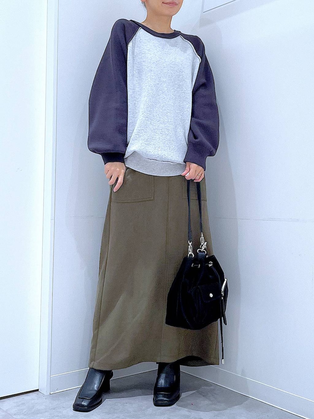 ブラック系のショルダーバッグ、グレー系のニット/セーター、ブラック系のブーツを着用したレディースの冬コーディネートの6枚目の写真