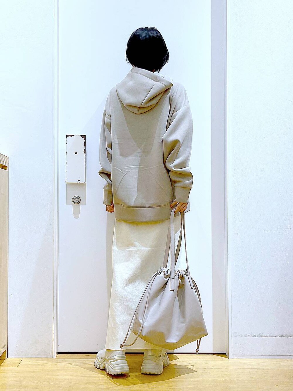 ベージュ系のトートバッグ、ベージュ系のブーツ、ベージュ系のスカートを着用したレディースの秋コーディネートの5枚目の写真