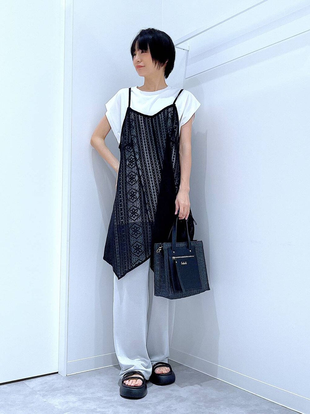 ブラック系のショルダーバッグ、ブラック系のサンダル、ホワイト系のTシャツ/カットソーを着用したレディースの夏コーディネートの2枚目の写真