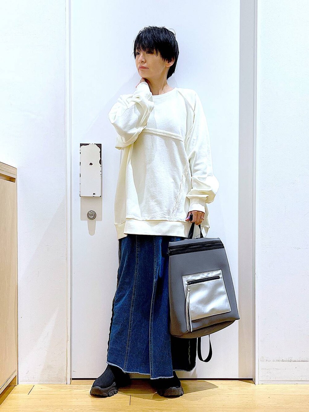 ブルー系のデニムスカート、グレー系のバックパック/リュック、ブラック系のブーツを着用したレディースの冬コーディネートの2枚目の写真