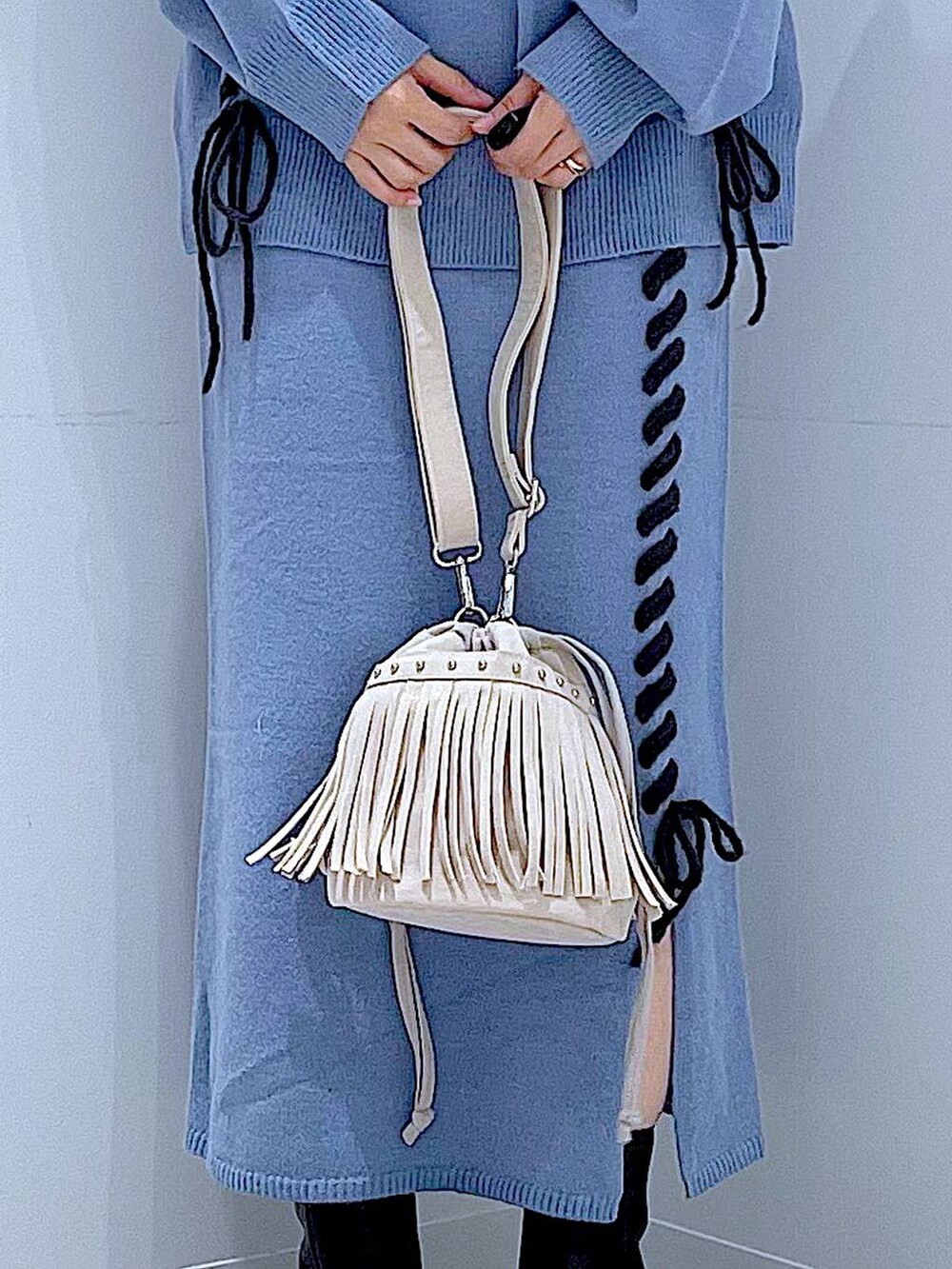 ブルー系のニット/セーター、ブルー系のスカート、ブラック系のブーツを着用したレディースの秋コーディネートの9枚目の写真