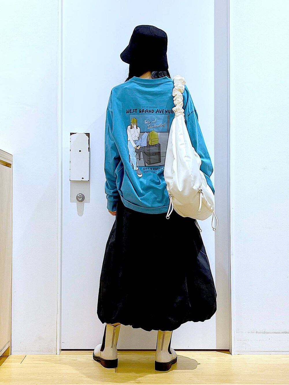 グリーン系のTシャツ/カットソー、ベージュ系のブーツ、ホワイト系のショルダーバッグを着用したレディースの春コーディネートの5枚目の写真