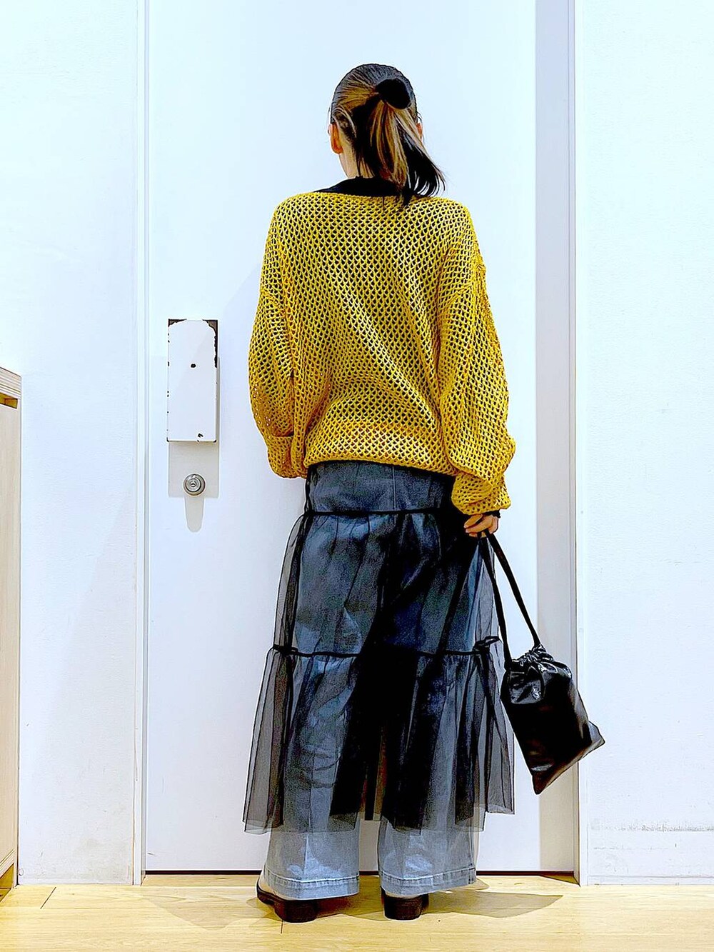 ブルー系のデニムパンツ、ブラック系のTシャツ/カットソー、オレンジ系のニット/セーターを着用したレディースの冬コーディネートの5枚目の写真