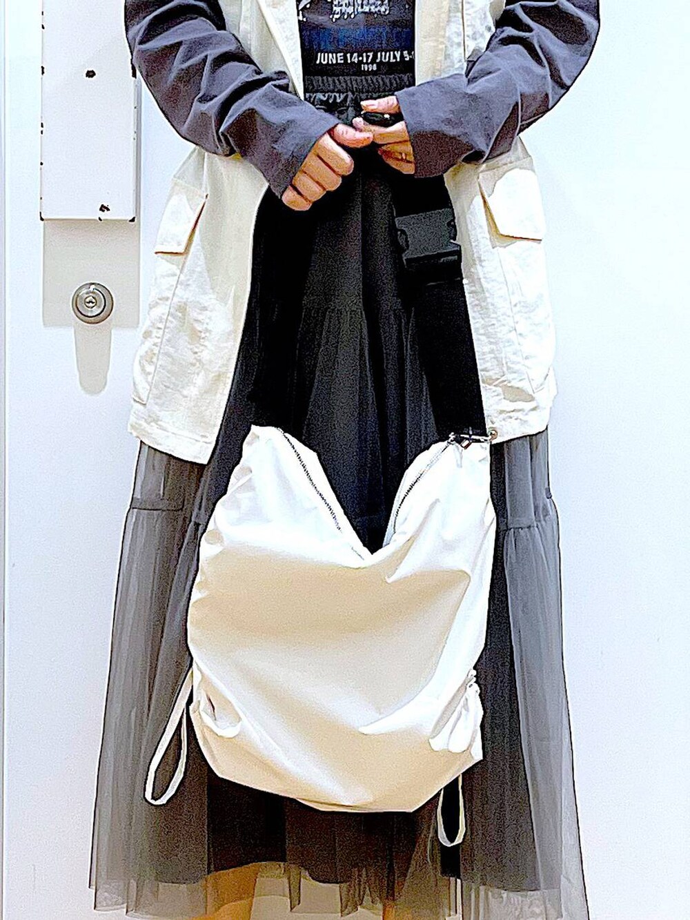 グレー系のスカート、ブラック系のスニーカー、ホワイト系のベストを着用したレディースの春コーディネートの9枚目の写真