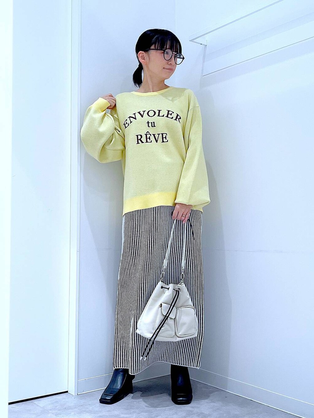 ホワイト系のショルダーバッグ、ベージュ系のスカート、ブラック系のブーツを着用したレディースの冬コーディネートの2枚目の写真