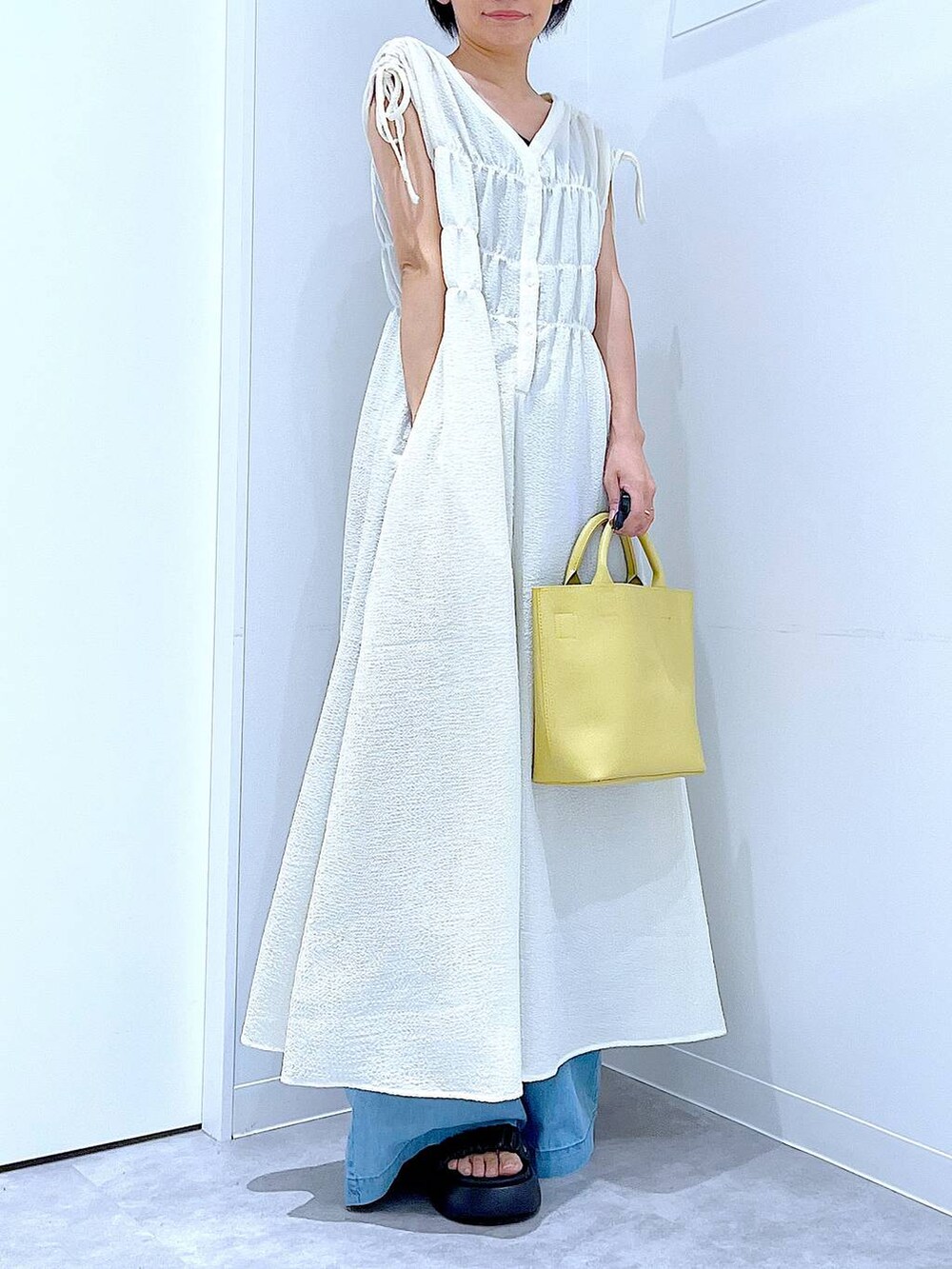 ブラック系のサンダル、ブルー系のデニムパンツ、ベージュ系のワンピースを着用したレディースの夏コーディネートの6枚目の写真