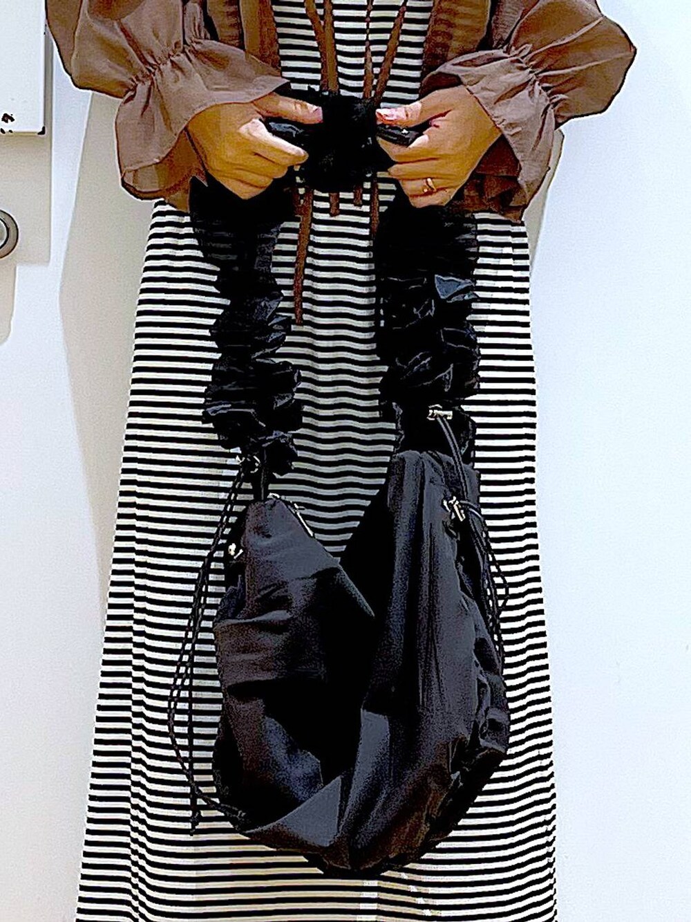 ブラック系のワンピース、シルバー系のパンプス、ブラック系のショルダーバッグを着用したレディースの夏コーディネートの9枚目の写真