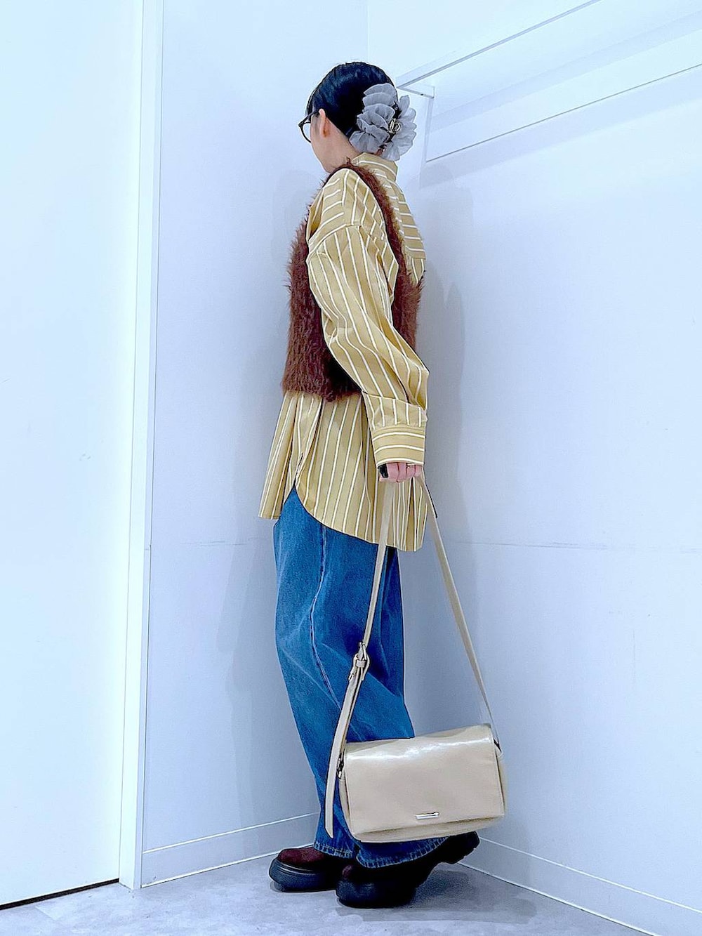 ブルー系のデニムパンツ、イエロー系のシャツ/ブラウス、ブラウン系のベストを着用したレディースの秋コーディネートの3枚目の写真