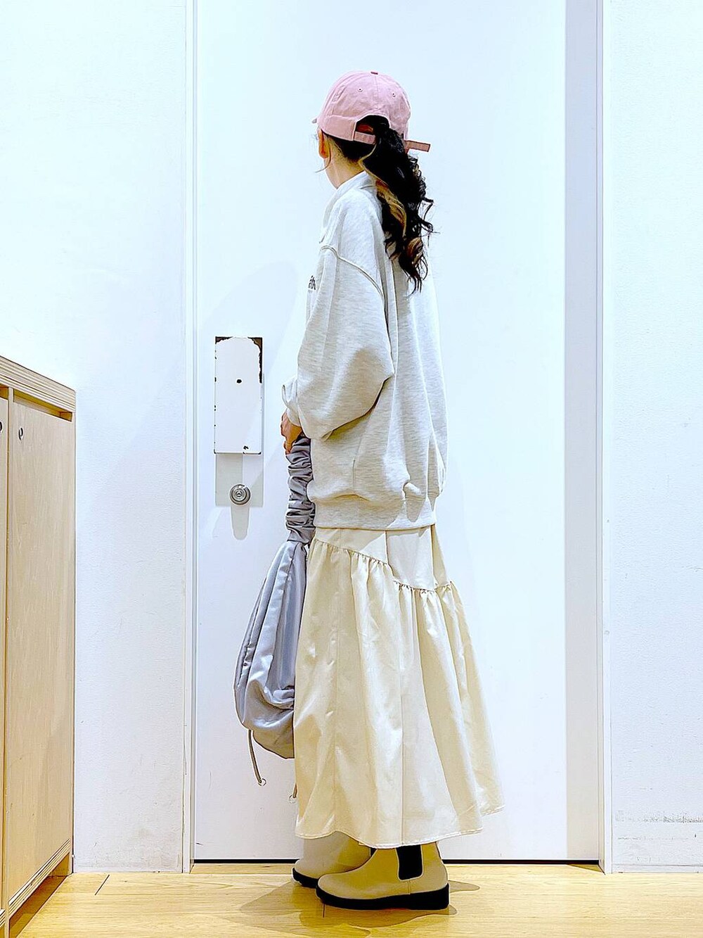 ベージュ系のスウェット、ホワイト系のスカート、ベージュ系のブーツを着用したレディースの春コーディネートの3枚目の写真